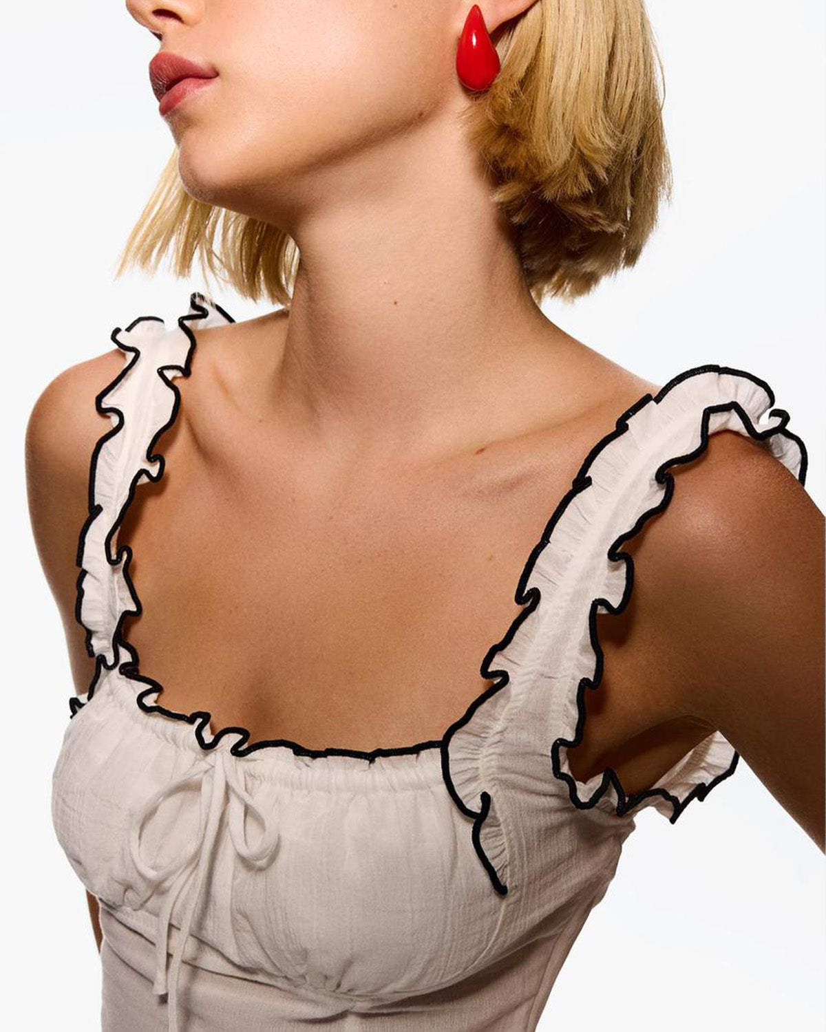 ruffled-edge-crop-top-white,topwear,tops,casual,soft girl,woven,cotton crepe,white,solid,ruffled,slim fit,crop,crop,square neck,shoulder strap,sleeveless,Color: White
Fabric: Cotton Crepe
Fit: Slim Fit 
Length: Crop
Neck: Square Neck
Print: Solid
Details: Ruffled edges in black creates a striking contrast, the square neckline features subtle gather and drawstring for added detail,RUFFLED EDGE CROP TOP