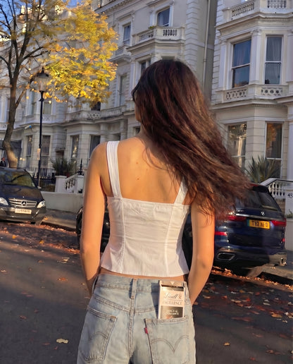 pinktuck-detail-slit-top-white,topwear,tops,casual,streetwear,woven,Stretchable,poplin,white,solid,ruched,regular fit,slit,regular,slit,square neck,shoulder strap,sleeveless,Color: White
Fabric: Poplin
Fit: Skinny Fit 
Length: Regular
Neck: Square Neck
Closure: Hook & Eye
Print: Solid
Details: Pintuck seam detailing adds texture and structure. The contrast bow tie at the center adds a feminine touch.,PINKTUCK DETAIL SLIT TOP